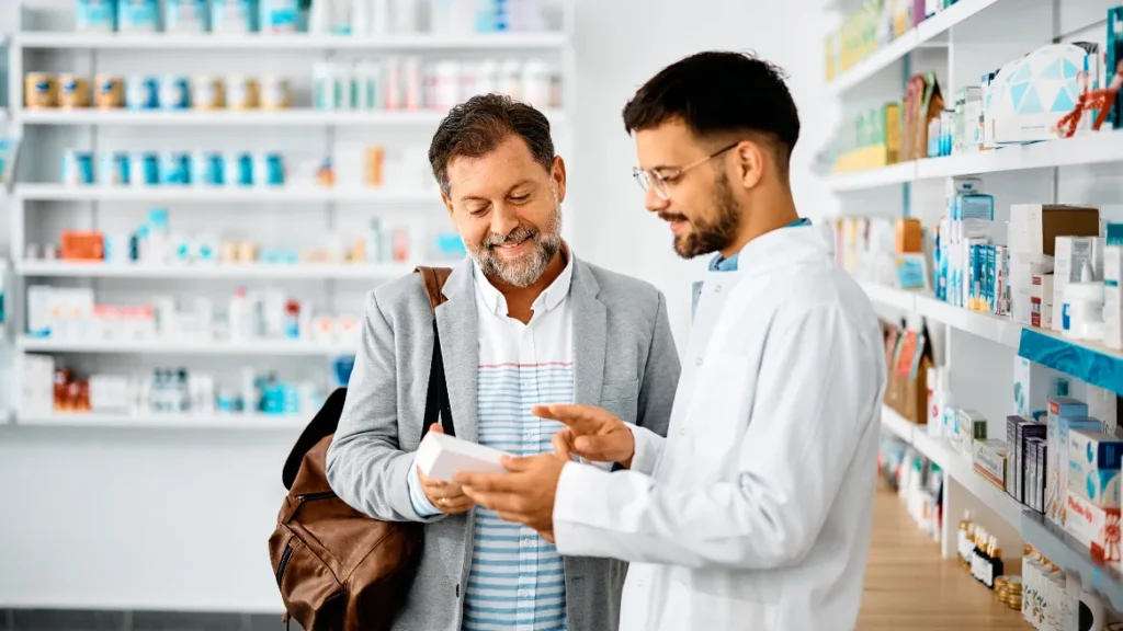 Pharmacist discussing medicine with customer inside Kingsland Pharmacy, Mary Street, Southampton.