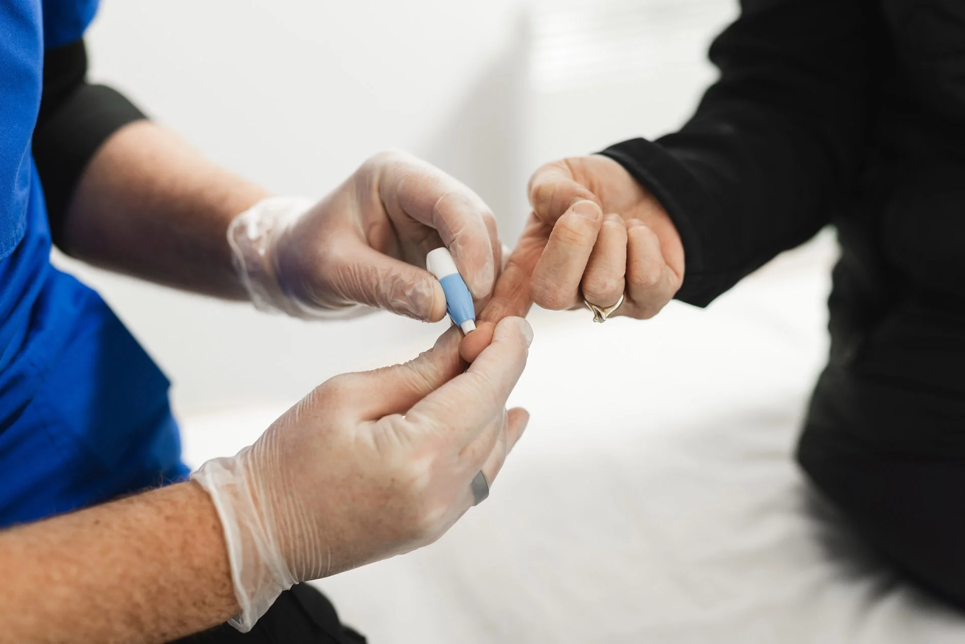 Finger‑prick blood test being performed with lancet device on fingertip.