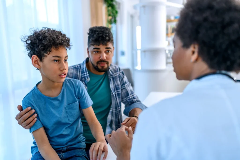 Healthcare professional consulting with child and guardian in a bright medical setting