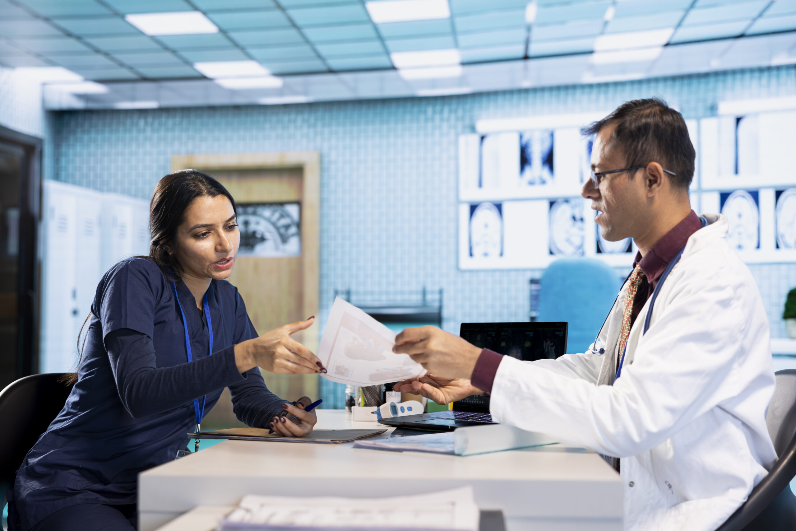 Doctor and nurse reviewing patient documents together in a hospital workspace.