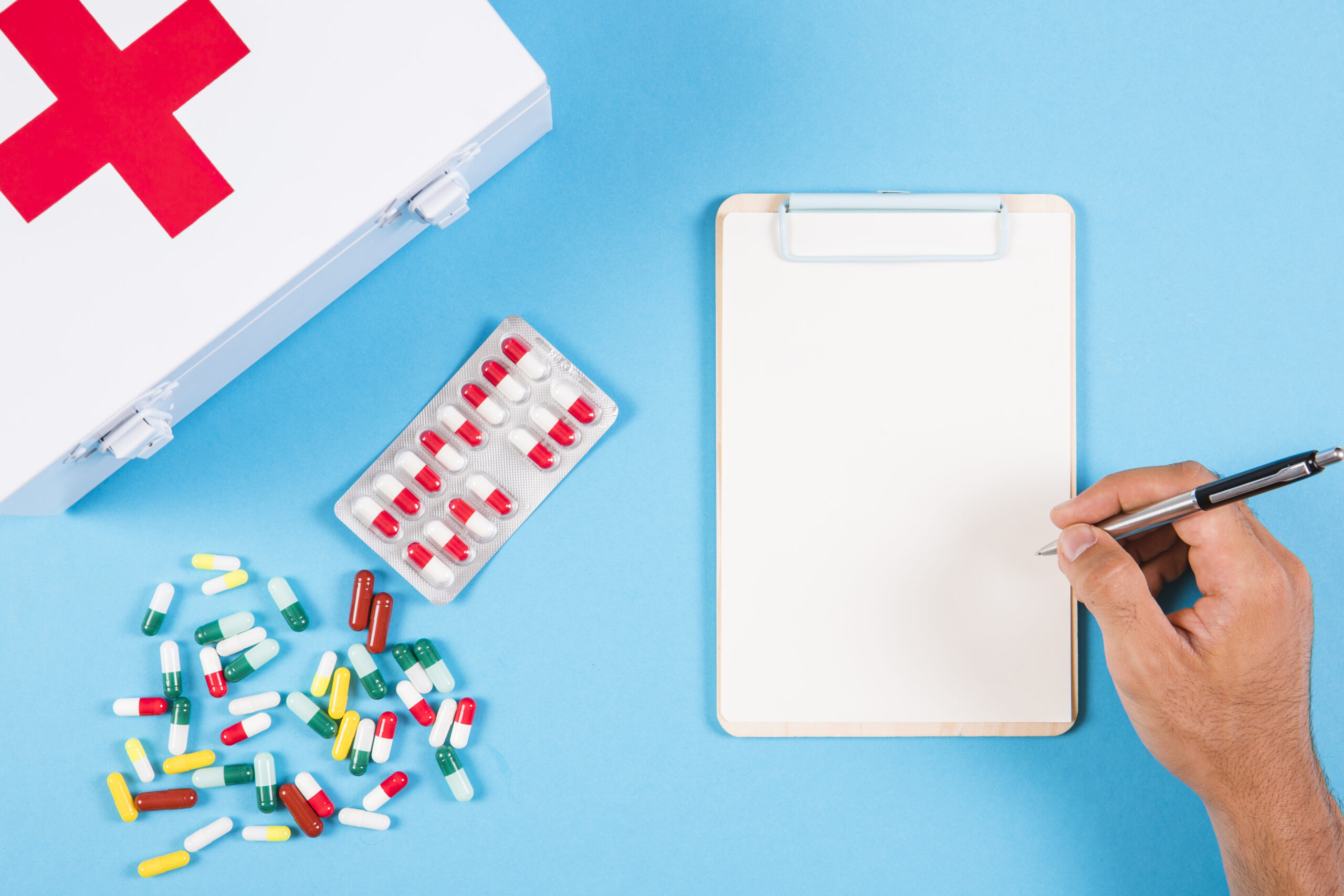 Clipboard and first aid kit with scattered pills representing medication management at Kingsland Pharmacy, Mary Street, Southampton.